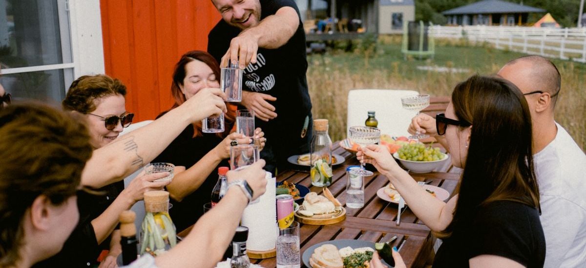 A joyful outdoor gathering with friends clinking glasses over a shared meal.