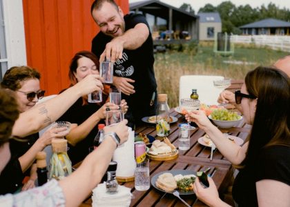 A joyful outdoor gathering with friends clinking glasses over a shared meal.