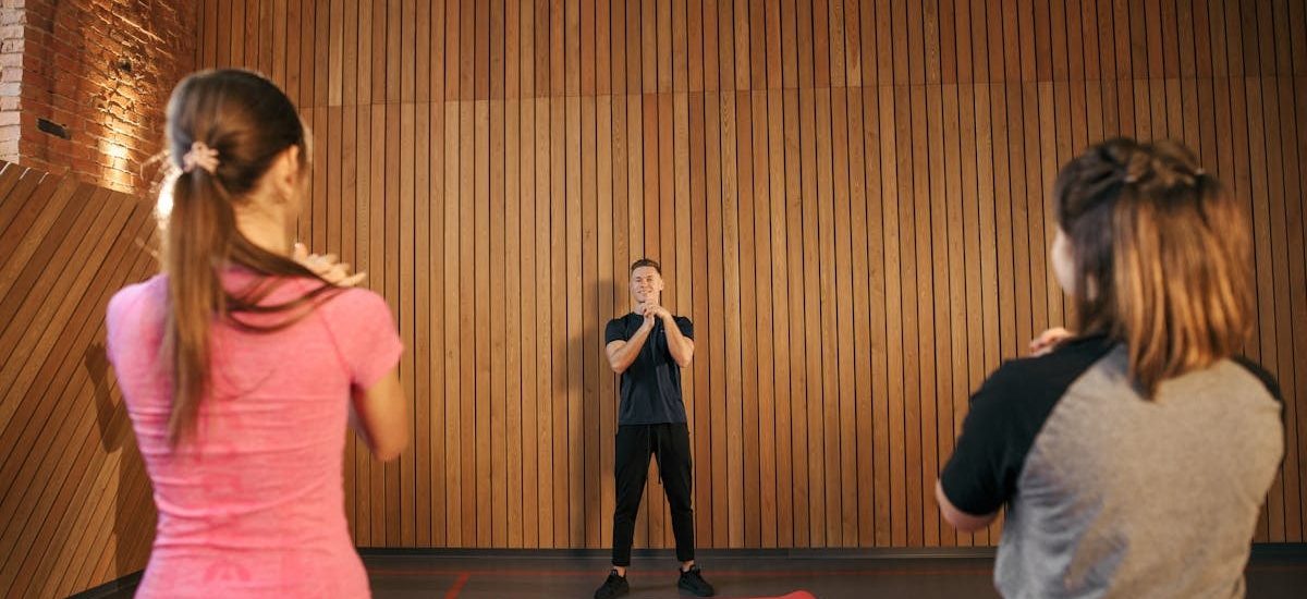 Fitness instructor leading a training session with two women in a modern gym setting.