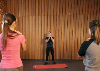 Fitness instructor leading a training session with two women in a modern gym setting.